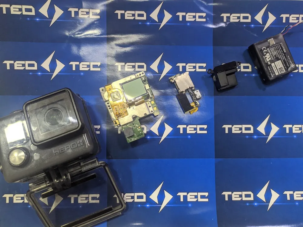 GoPro Hero desarmada en el laboratorio de TeoTec: placa, módulo de pantalla, conector y batería